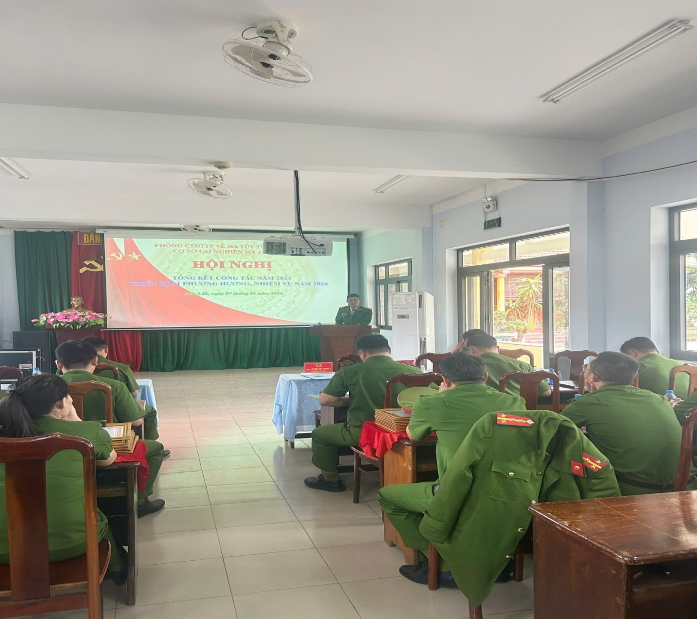 '''A group of people in green uniforms sitting in a room
 Description automatically generated'''