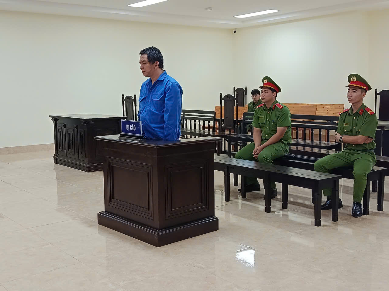 'A person in a blue shirt standing in a courtroom
 AI-generated content may be incorrect.'